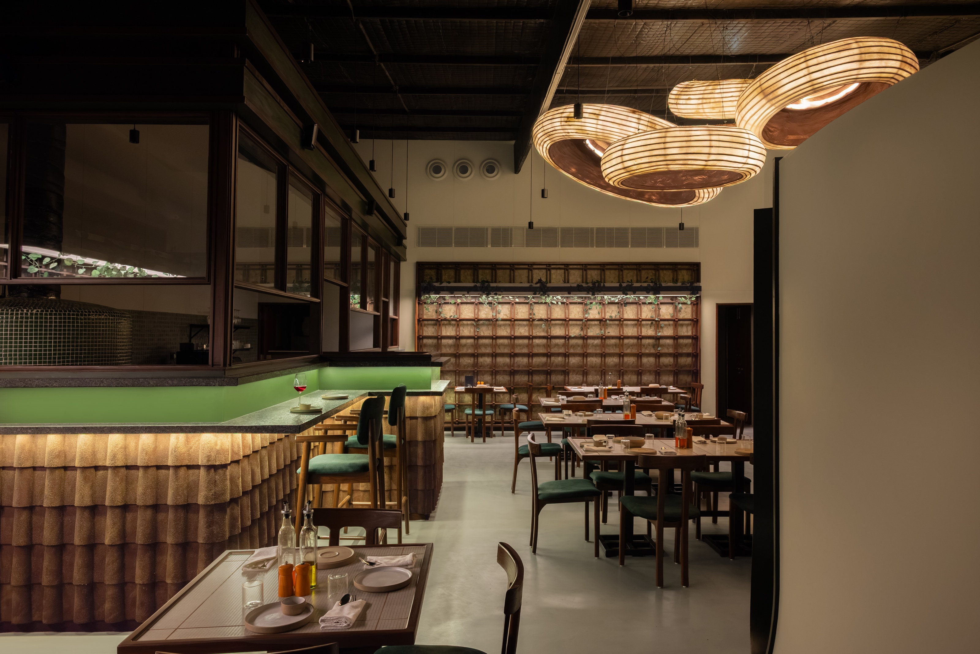 Adoro dining room under its woven pendant cluster, beside the tiled bar